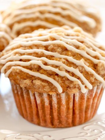 Three of the best ever pumpkin muffins topped with vanilla glaze on a white plate.