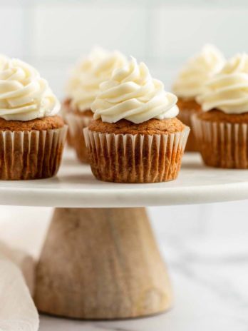 Pumpkin cupcakes sitting on top of a marble cake stand.