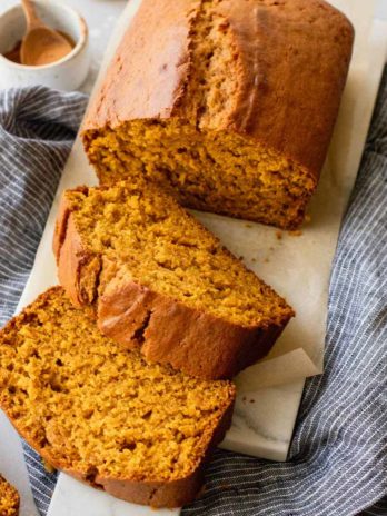 A loaf of pumpkin bread that has been sliced on a marble serving tray.